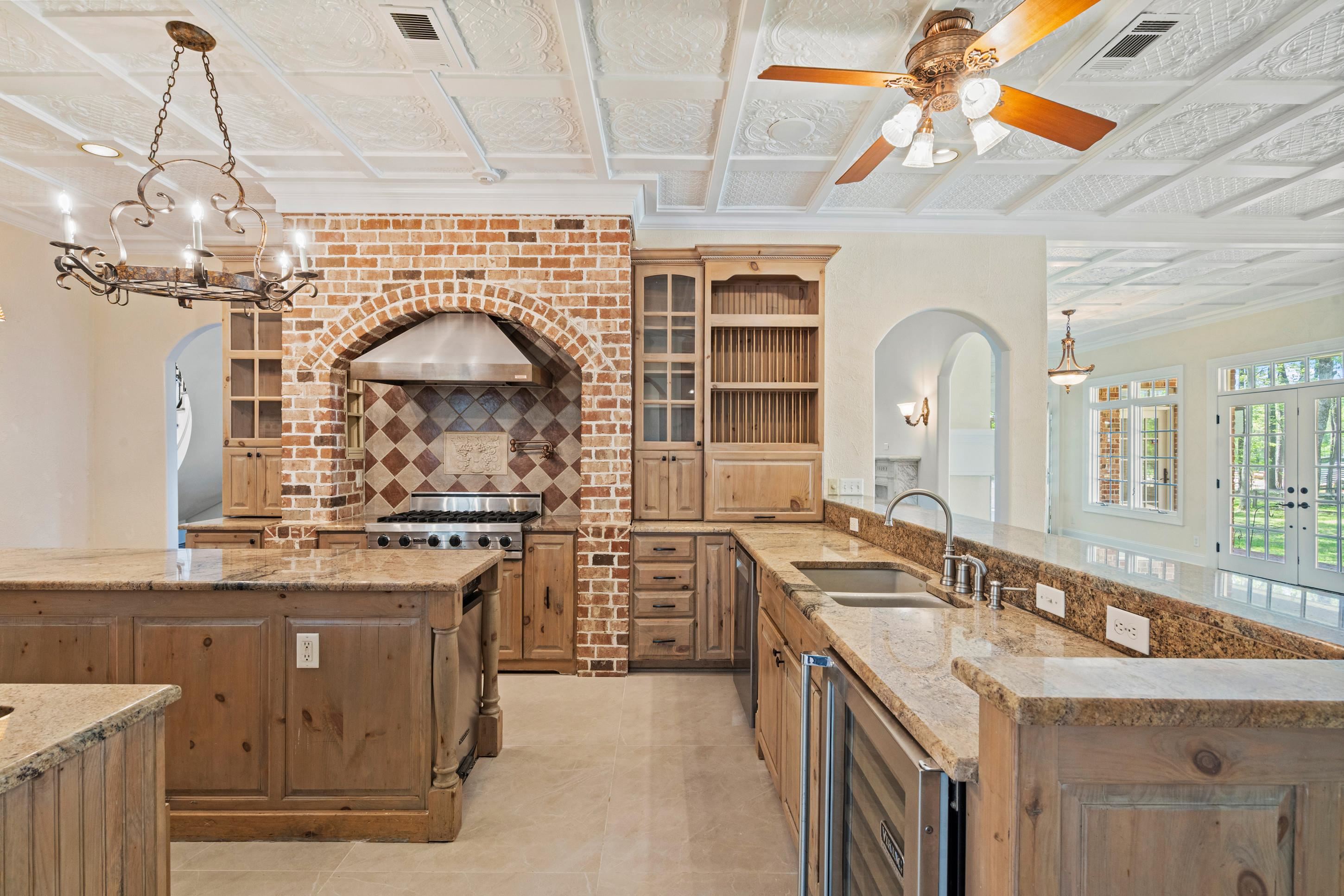815 Dent Road Eads, TN 38028 - Photo 13 of 40 Kitchen with light stone countertops, wine cooler, crown molding, glass insert cabinets, and decorative backsplash