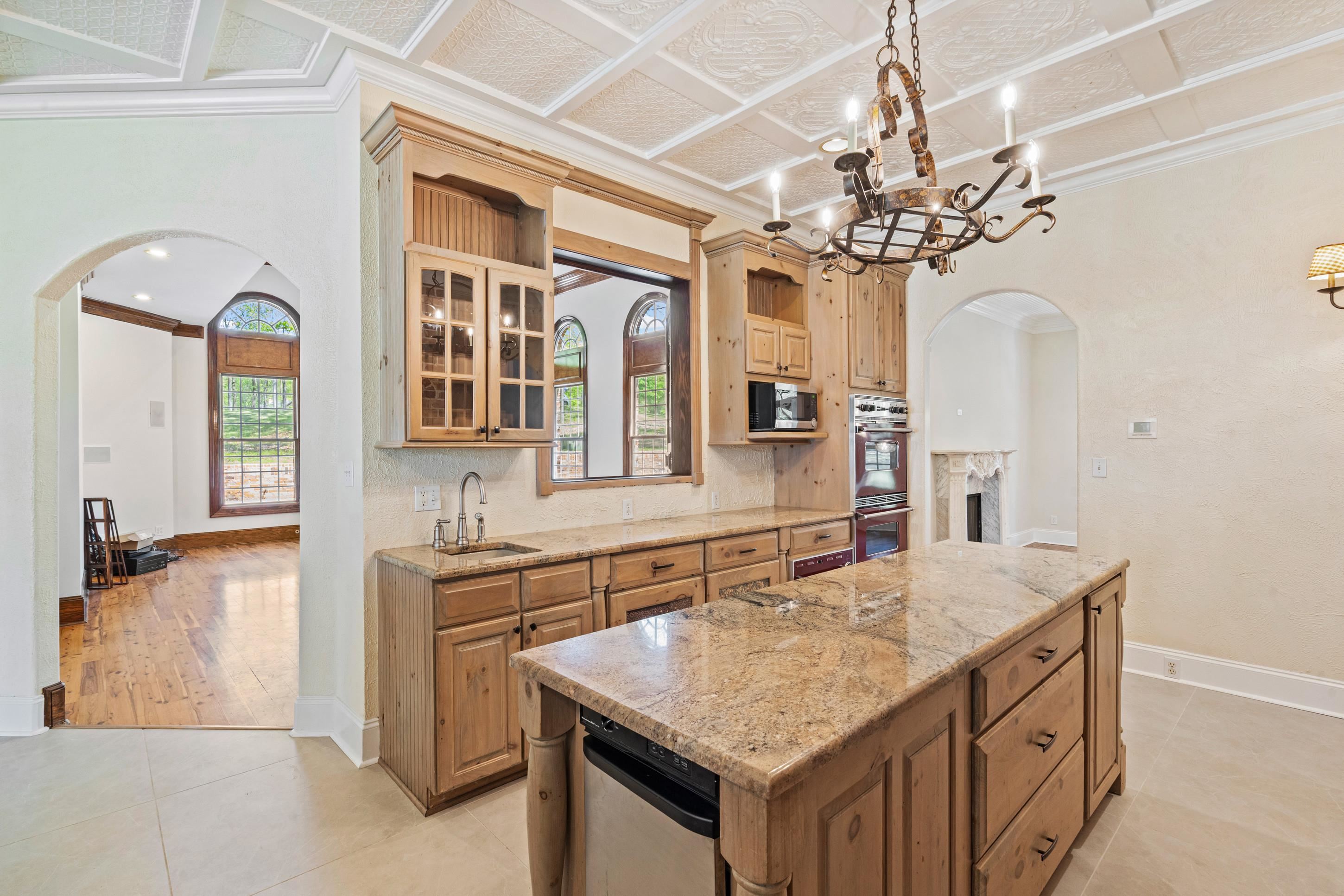 815 Dent Road Eads, TN 38028 - Photo 14 of 40 Kitchen with arched walkways, light stone counters, glass fronted cabinets, crown molding, and a chandelier