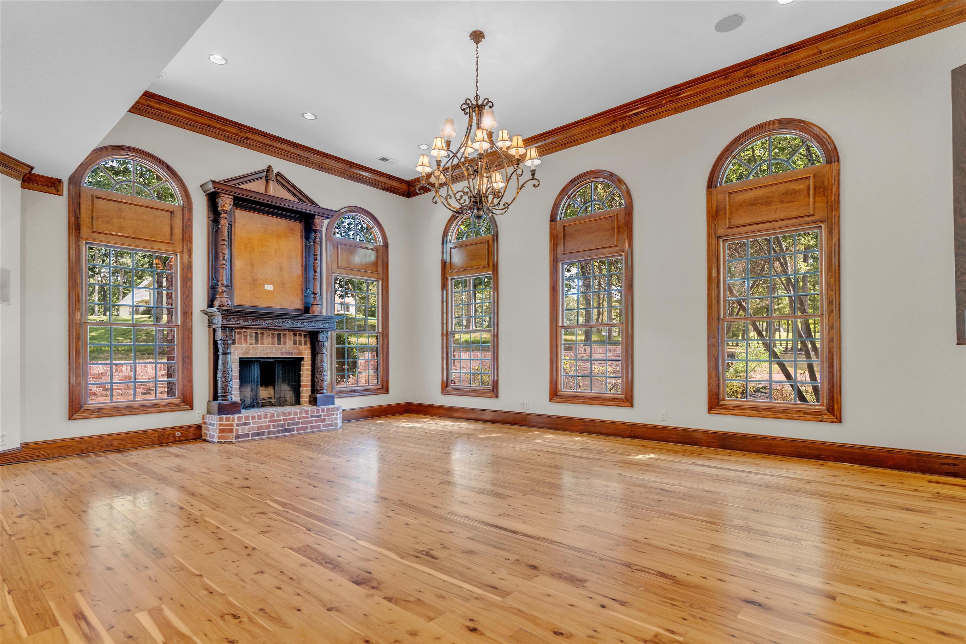 815 Dent Road Eads, TN 38028 - Photo 16 of 40 Unfurnished living room with light wood-type flooring, crown molding, healthy amount of natural light, a chandelier, and a fireplace