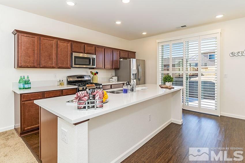 9260 Peninsula Court Reno, NV 89506 - Photo 9 of 25 a kitchen with stainless steel appliances a sink a stove a refrigerator cabinets and a dining table