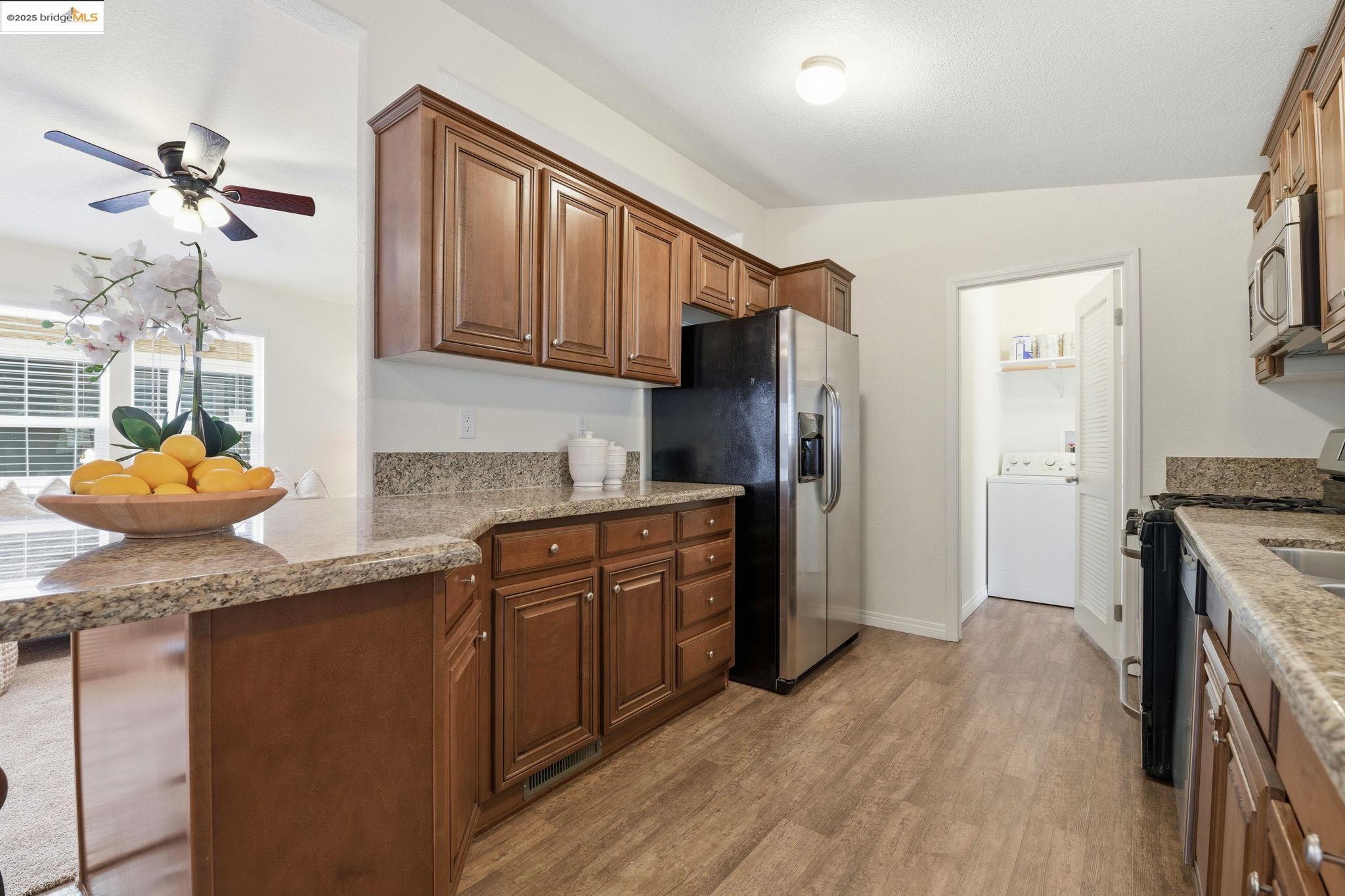 16711 Marsh Creek Road, Unit 111 Clayton, CA 94517 - Photo 15 of 34 a kitchen with stainless steel appliances granite countertop a refrigerator a sink dishwasher a stove and a dining table with wooden floor