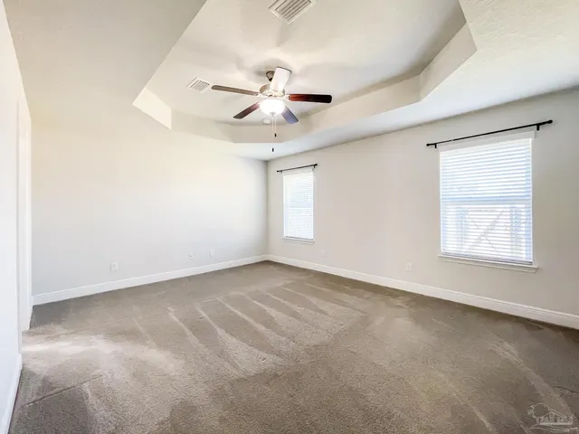 an empty room with windows and fan