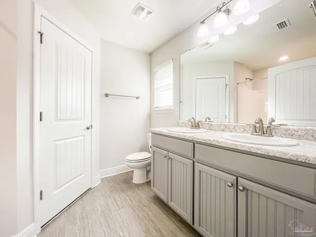 a bathroom with a granite countertop sink a toilet and a mirror