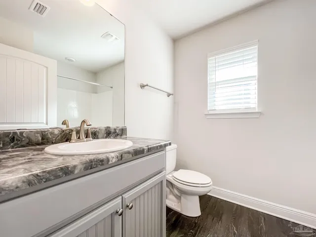 a bathroom with a granite countertop toilet a sink and a mirror