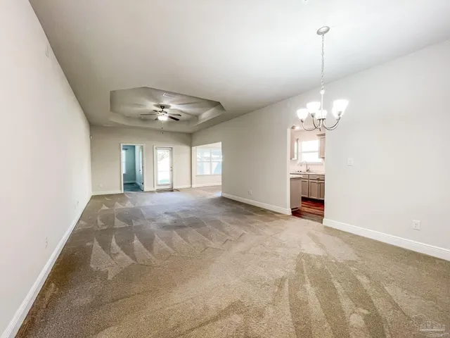 a view of a livingroom with a chandelier fan and windows