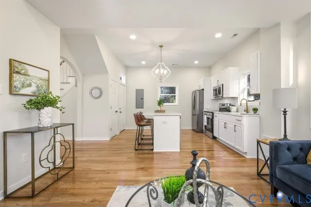 a living room with furniture kitchen view and a wooden floor