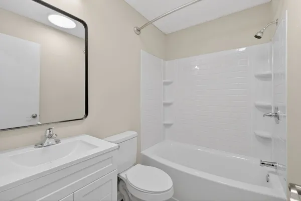 a bathroom with a bathtub shower sink vanity mirror and toilet