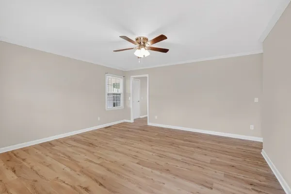 a view of an empty room with window and a ceiling fan