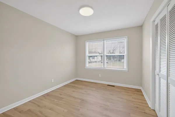 an empty room with wooden floor and windows
