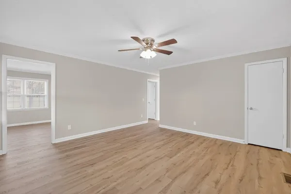 an empty room with wooden floor and a ceiling fan