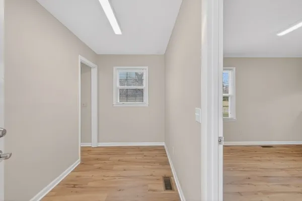 a view of an empty room with wooden floor and a window