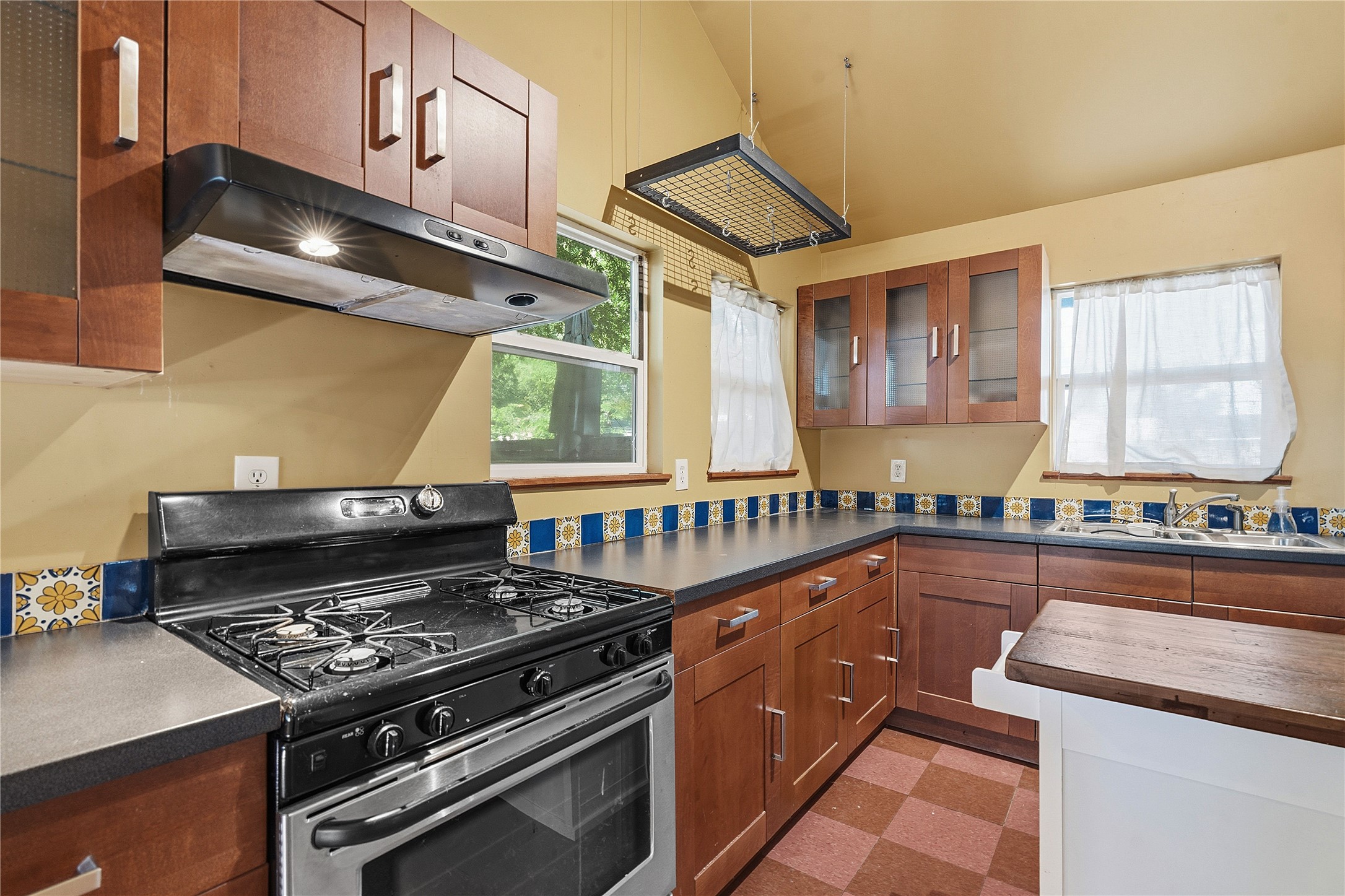 2207 Santa Rita Street Austin, TX 78702 - Photo 4 of 15 Kitchen with wood cabinetry, dark countertops, and a full-size range with an overhead hood vent