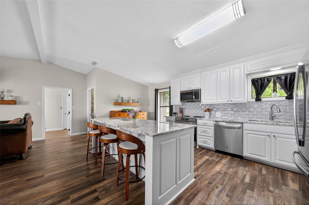 23363 Wateridge Loop Flint, TX 75762 - Photo 22 of 40 a kitchen with stainless steel appliances granite countertop a stove top oven a sink dishwasher a dining table and chairs with wooden floor