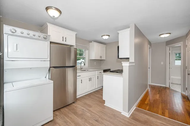 a kitchen with a refrigerator a stove top oven and a wooden floor
