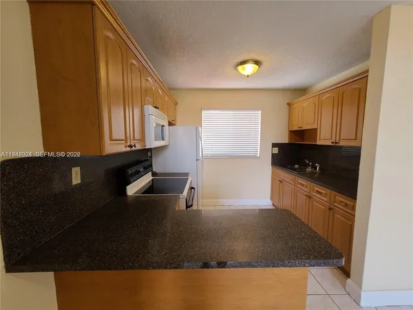a kitchen with granite countertop white cabinets and black appliances