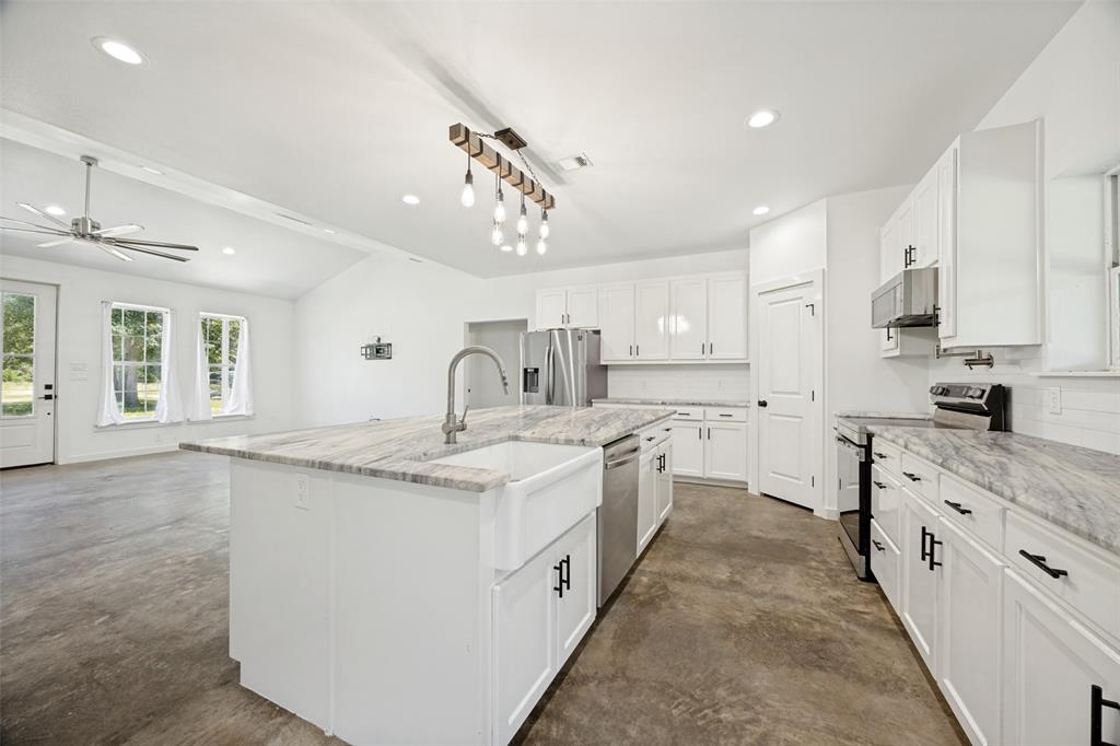 822 Private Road 7370 Point, TX 75472 - Photo 14 of 30 Kitchen featuring a large island with an apron-front sink and high-arc faucet, white cabinetry, stainless steel appliances, and light-toned countertops