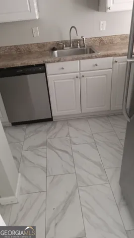 a white kitchen with granite countertop a sink a stove and white cabinets