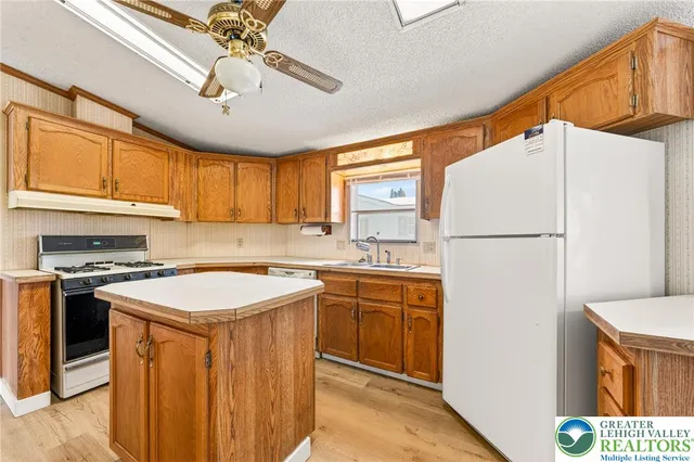 a kitchen with stainless steel appliances granite countertop a refrigerator a sink dishwasher a stove top oven a dining table and chairs with wooden floor