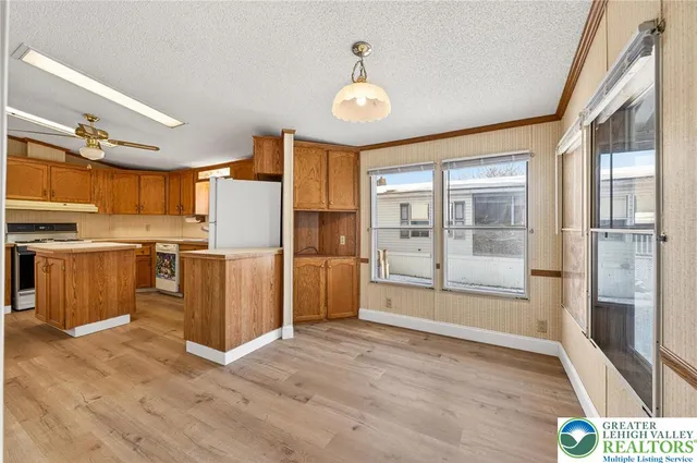 a view of kitchen with stainless steel appliances granite countertop a refrigerator a oven a sink with wooden floors and wooden cabinets
