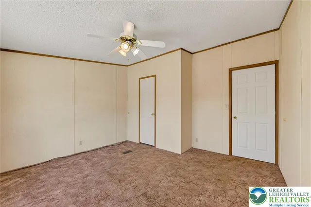 a view of an empty room and chandelier fan