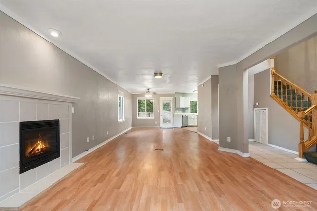 a view of an empty room with wooden floor fireplace and a window