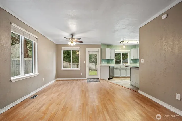 a view of an empty room with a window and wooden floor