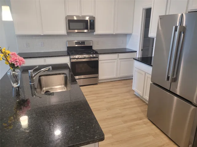 a kitchen with granite countertop a refrigerator stove and sink
