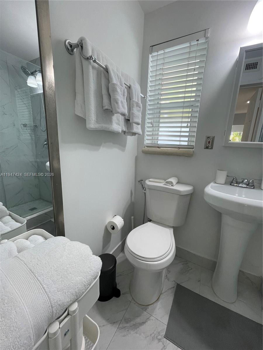 8036 Harding Avenue, Unit 1 Miami Beach, FL 33141 - Photo 24 of 33 a bathroom with a toilet sink and mirror