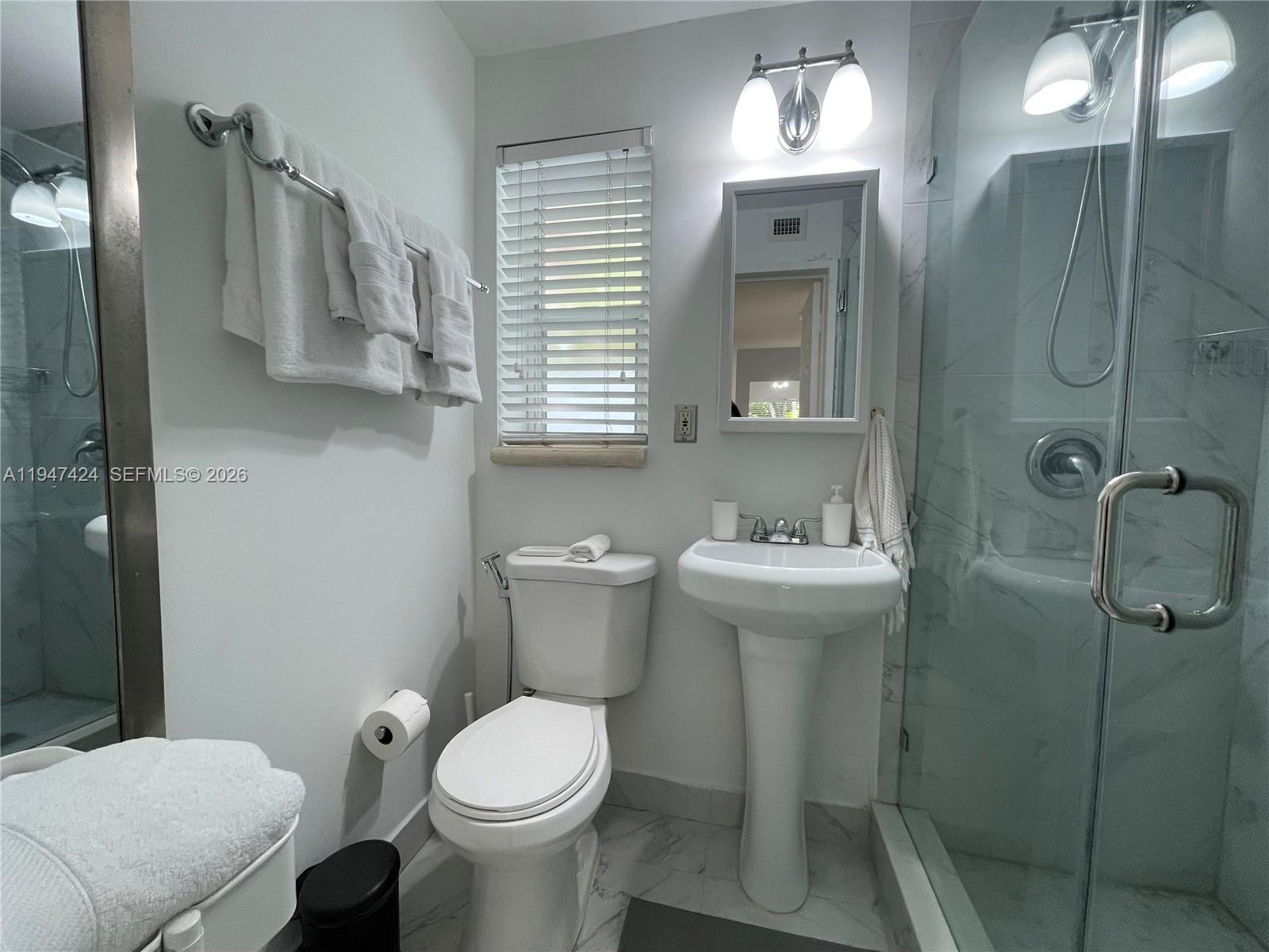 8036 Harding Avenue, Unit 1 Miami Beach, FL 33141 - Photo 25 of 33 a bathroom with a toilet sink and mirror