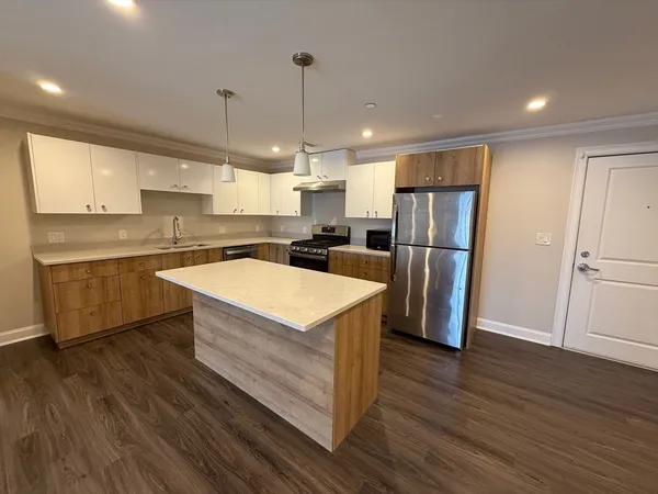 a kitchen with wooden cabinets a sink appliances and wooden floor