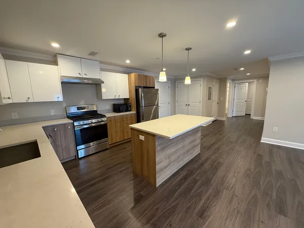 a large kitchen with kitchen island a stove a sink a refrigerator and a living room view