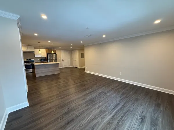 an empty room with wooden floor and kitchen
