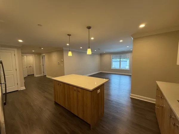 a kitchen with kitchen island a sink wooden floor and a refrigerator