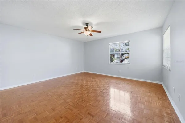 an empty room with windows and fan