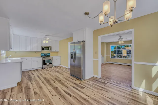 a kitchen with stainless steel appliances wooden floor and large windows