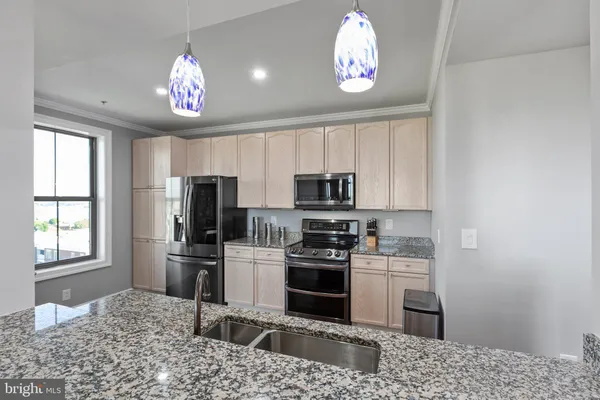 a kitchen with stainless steel appliances kitchen island granite countertop a sink stove and refrigerator