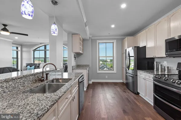 a kitchen with kitchen island granite countertop a sink appliances cabinets and a counter top space