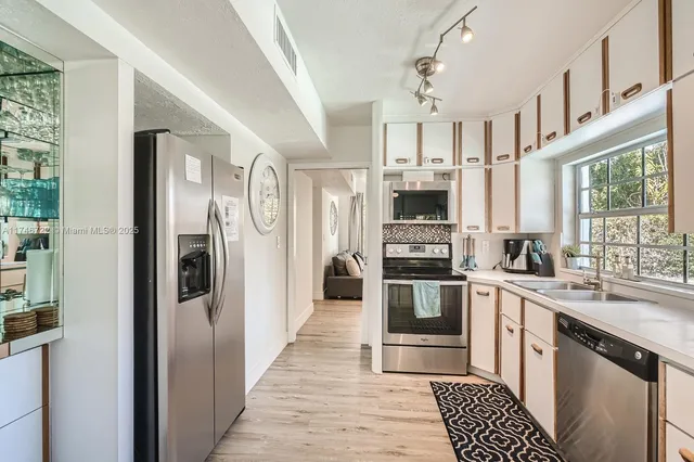 a kitchen with stainless steel appliances granite countertop a refrigerator a stove and a sink