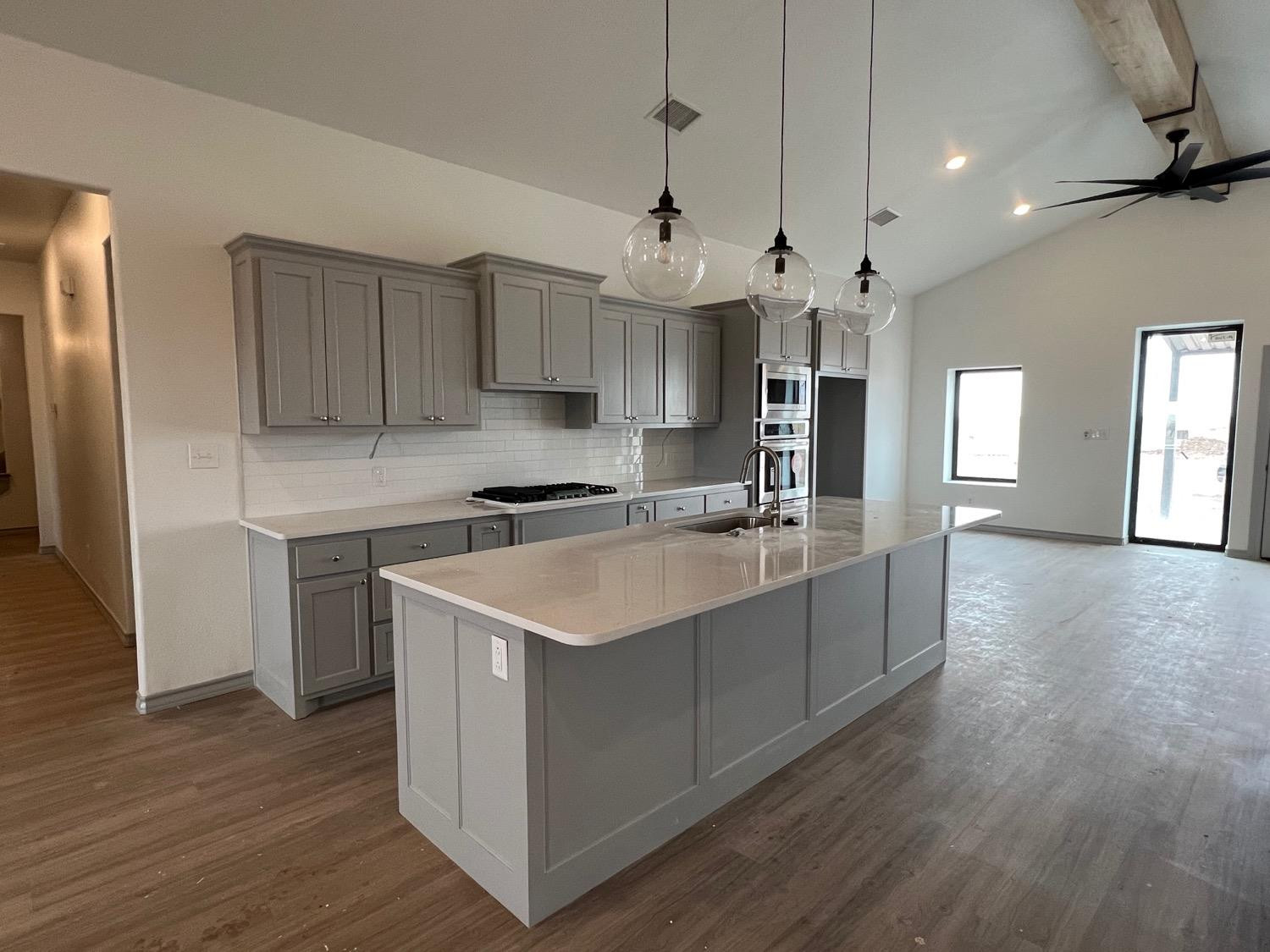 21402 County Road 2140 Lubbock, TX 79423 - Photo 4 of 23 a large kitchen with stainless steel appliances a sink dishwasher a refrigerator and a stove with wooden floor