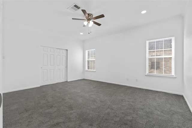 an empty room with windows and fan