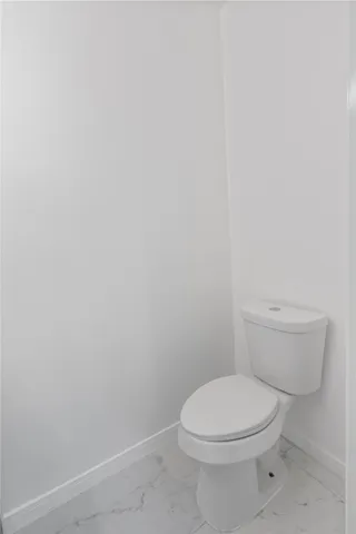 a white toilet sitting next to a white wall
