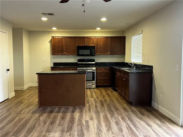 a kitchen with stainless steel appliances granite countertop a stove a sink and a microwave