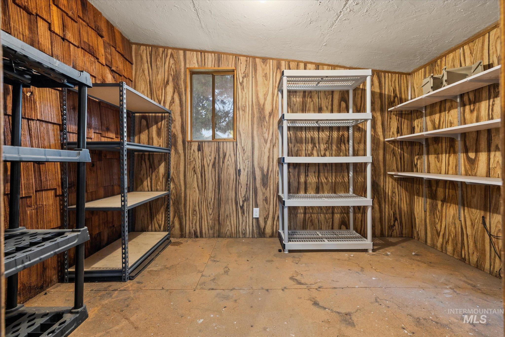 2302 Pendleton Street Boise, ID 83705 - Photo 34 of 35 Utility room featuring wood-finish wall paneling, a small window, built-in shelving, and exposed concrete flooring
