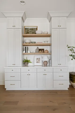 a kitchen with white cabinets and wooden floor
