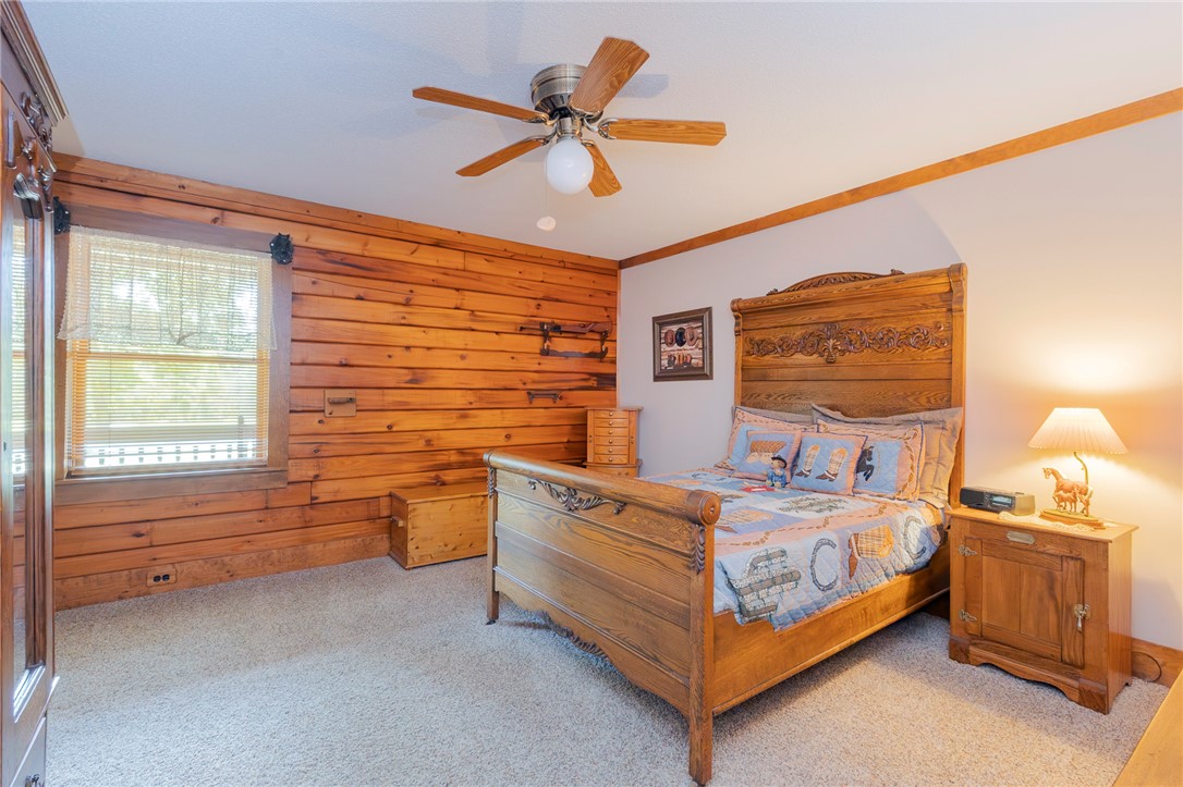 911 State Rd S-4-203 Belton, SC 29627 - Photo 20 of 49 A well-lit bedroom featuring natural wood paneling and a detailed wooden bed frame.