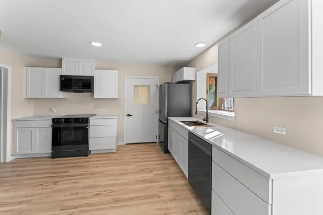 a kitchen with granite countertop a stove top oven and refrigerator