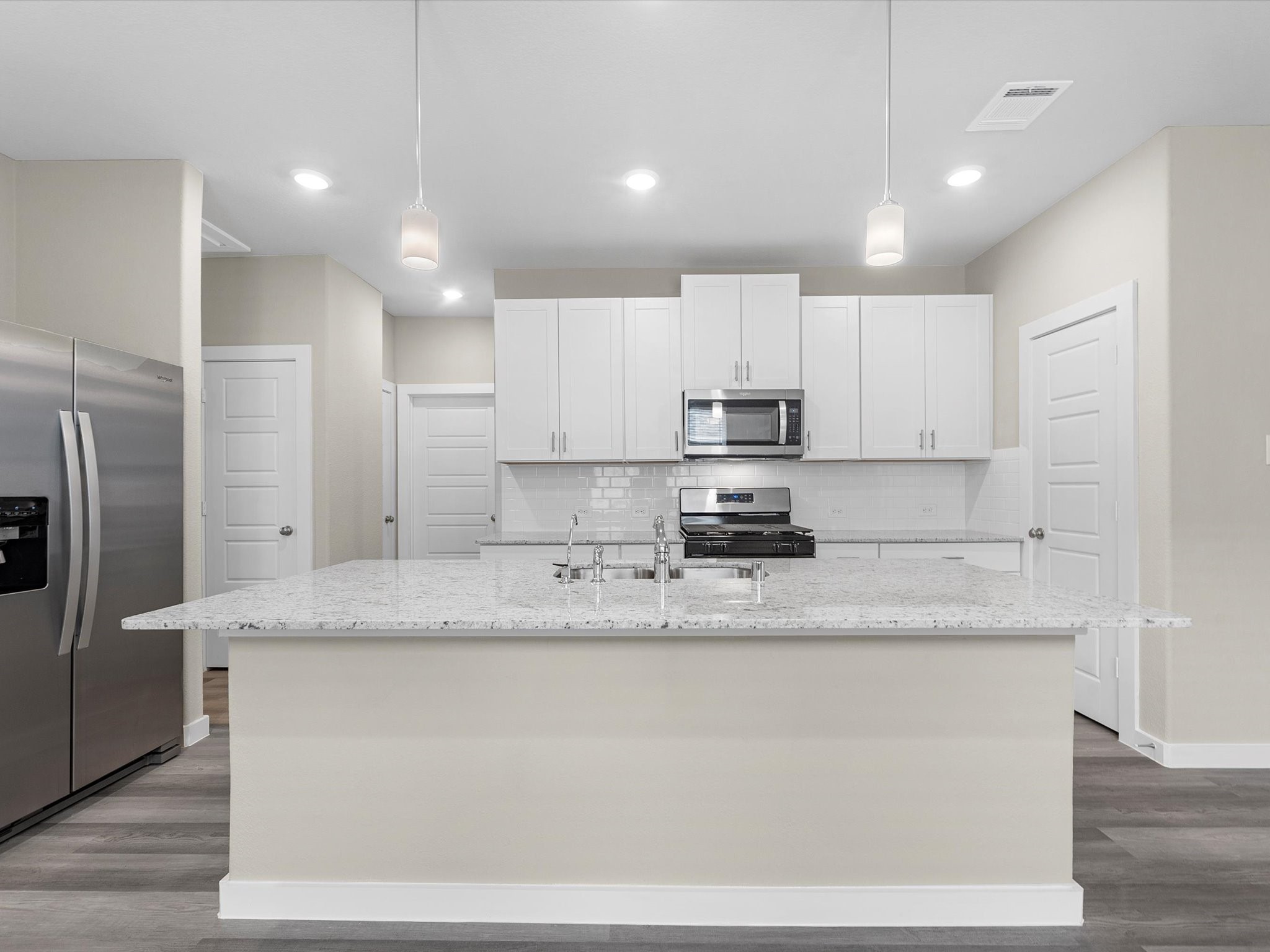 1749 Succotash Oak Court Conroe, TX 77304 - Photo 7 of 21 a kitchen with stainless steel appliances granite countertop a sink a refrigerator and white cabinets