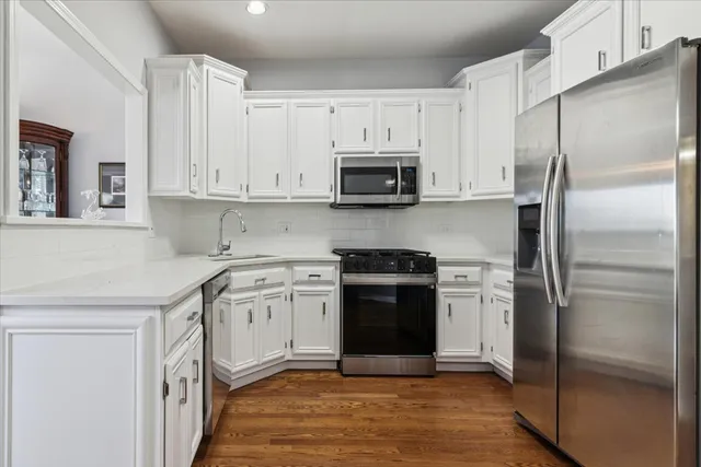 a kitchen with stainless steel appliances granite countertop a refrigerator a stove a sink and white cabinets