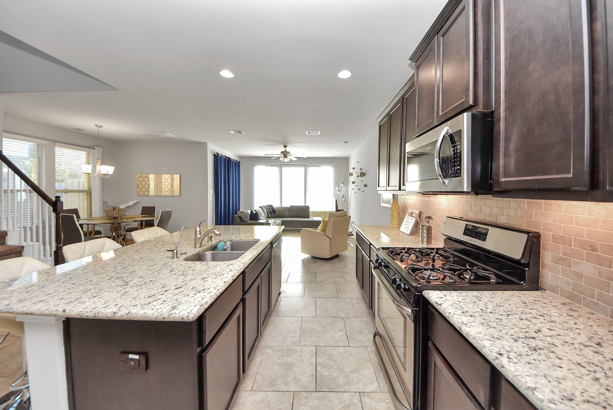 3310 Rainflower Springs Lane Rosenberg, TX 77471 - Photo 31 of 31 View from the kitchen island into the dining and living areas, showcasing a seamless open floor plan with natural light pouring in.
