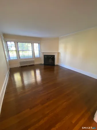 an empty room with wooden floor and a fireplace